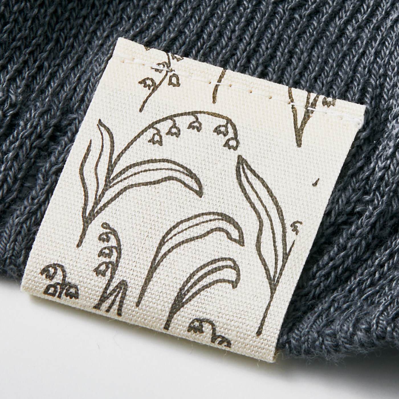 SAANA JA OLLI|サーナ ヤ オッリ　澄んだ空気をまとう軽やかさ　オーガニックコットン100％のニットベスト〈インクネイビー〉|PATTERN／Lily of the Valley　すそのブランドネームがリニューアル、春を告げるスズランの柄がさりげなくあしらわれて。※写真はイメージです。お届けするカラーとは異なります。