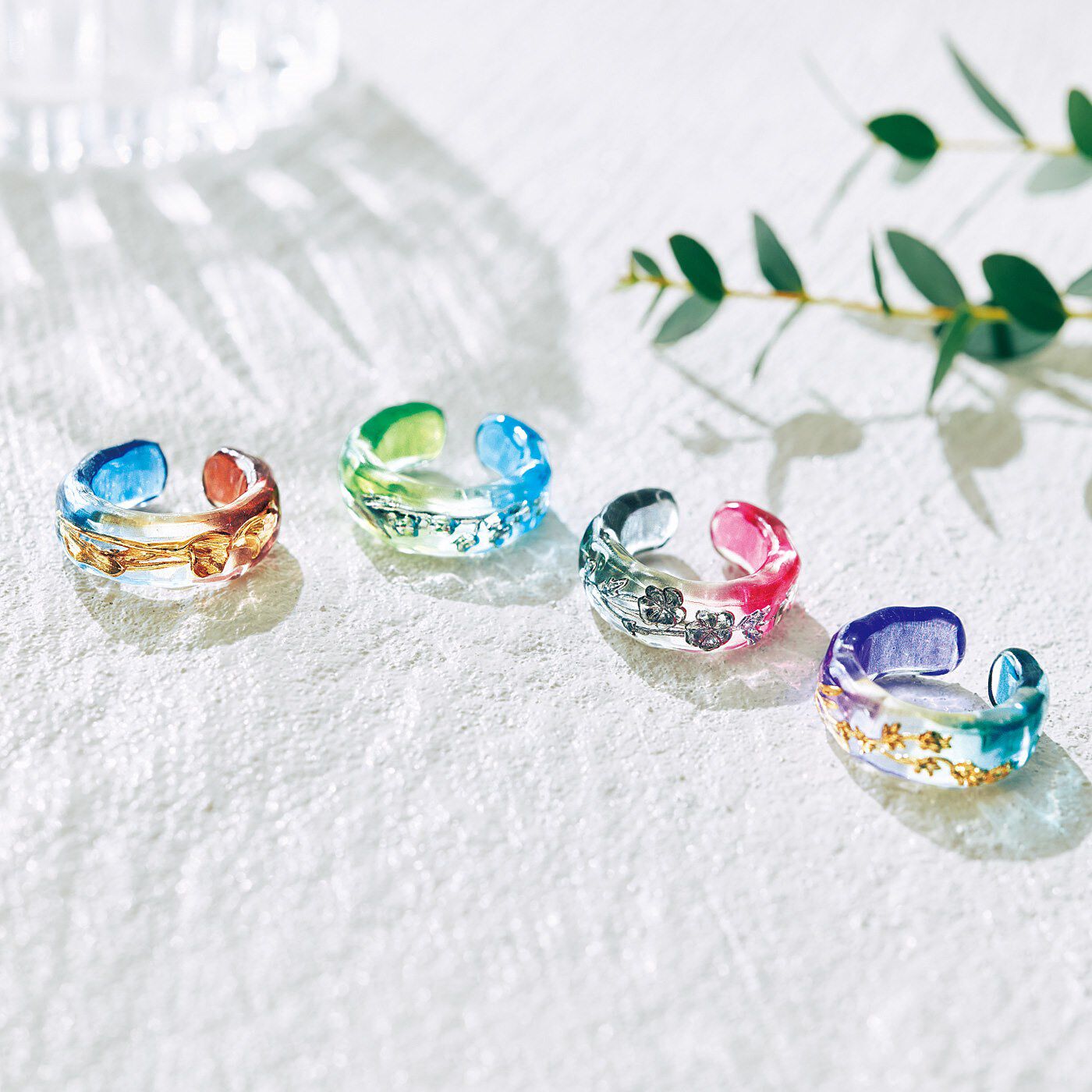 指先や耳もとにうるわしい花をたずさえて2色のグラデーションのクリア素材の中に咲く、繊細なお花のモチーフ。リングとしてもイヤカフとしても使えて、手もとや耳もとでみずみずしくきらめきます。金属が直接肌に当